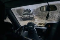 A Ukrainian tank with soldiers is seen through a car window.