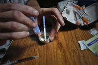 A drug user prepares heroin, placing a fentanyl test strip into the mixing container to check for contamination