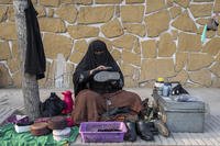 An Afghan woman cleans customers' shoes in a street in Kabul.
