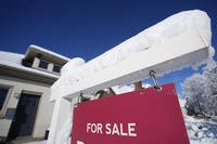 A layer of wet, heavy snow tops the arm of a for-sale sign outside a home in Denver.