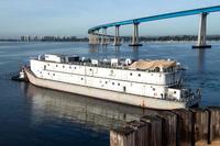 A tugboat tows a barge, assigned to amphibious assault ship USS Essex.