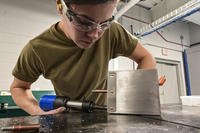 An aircraft structural technician uses a rivet gun to fasten pieces of metal while building a supply box at the Pittsburgh International Airport Air Reserve Station.