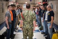 A Night of Arrivals staff member motivates new recruits as they line up inside the Golden 13 recruit in-processing center at U.S. Navy Recruit Training Command at Great Lakes, Ill.