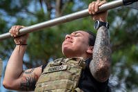 A U.S. Army adviser assigned to 1st Security Force Assistance Brigade and their families performs a pull-up at Fort Benning, Georgia. Fort Benning has since been renamed Fort Moore. 