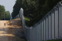 A Polish border guard patrols the area of a built metal wall on the border between Poland and Belarus
