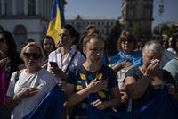 Women cry while listening to the Ukrainian national anthem at a protest