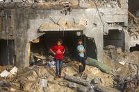 Palestinians inspect the damage of a destroyed house that was hit by an Israeli airstrike