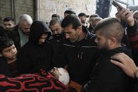 Palestinians stand around the body of a man killed during Israeli military raid.