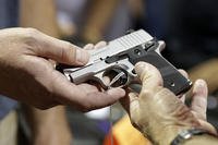 A gun seller shows a SIG Sauer handgun to a customer at a gun show in Miami.