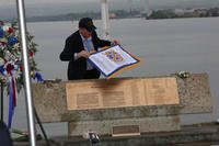 John Galloway places a flag with the names of the men who perished on December 7, 1941