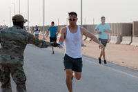 A U.S. Air Force airman assigned to the 378th Air Expeditionary Wing takes a water bottle while running a Memorial Day 5K at an undisclosed location within the U.S. Central Command area of responsibility.