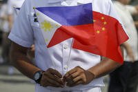 A member of the Philippine Coast Guard holds flags during the arrival of Chinese naval training ship.