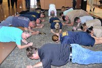 Civilians and active-duty service members take part in a plank challenge at Naval Health Clinic Charleston, S.C.