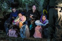 Asylum-seekers wait to board Border Patrol vehicles.