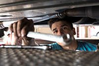 Senior Airman Igor Pacheco, 56th Medical Support Squadron lab technician, reaches for a wrench while replacing an exhaust system on his vehicle in the Auto Hobby Shop at Luke Air Force Base, Ariz.