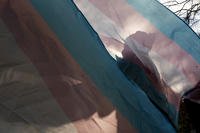Protester is silhouetted against a trans pride flag