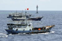 Chinese fishing vessels navigate past a beacon in the Zhubi Reef off Spratly Islands in South China Sea