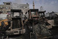 Palestinians examine the remains of bulldozers hit by an Israeli army airstrike in Jabaliya
