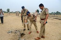 Indian police personnel inspect an object.