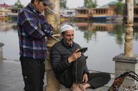 Kashmiri men watch news on a cell phone at Dal lake in Srinagar, Indian controlled Kashmir