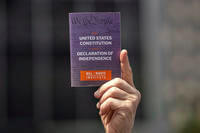 A person holds a copy of the Constitution of the United States of America and Declaration of Independence at a May Day rally for the Rule of Law