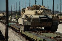 Soldiers guide an M1A1 Abrams on to a equipment transportation railcar