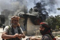 Bedouin fighters stand in front of a burned shop.