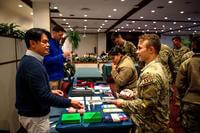 Advisers stand behind a table and talk to U.S. Air Force members.