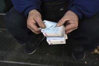 A street money exchanger poses for a photo without showing his face as he counts Iranian banknotes