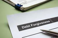 a printed sheet of paper labeled &quot;debt forgiveness&quot; is pictured on a desk