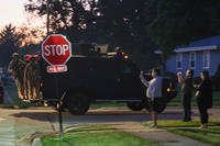 Federal agents hang off the back of a military-style vehicle as they, along with several other vehicles, drive south along Chippewa Drive on Sept. 16, 2025, in Elgin, Illinois.