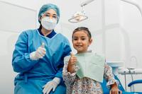 A dentist and child give thumbs-up signs.