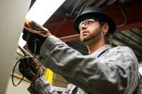 A man wearing safety gear manipulates wires.