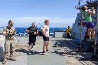 Four military members in workout gear do events of the Murph on a ship's deck.