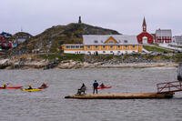 Tourists kayak at sea in front of Nuuk Cathedral in Nuuk, Greenland.