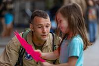 A Marine pictured with a little girl holding artwork.