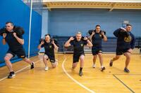Sailors in a gym do lunges with sandbags.