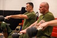 Marines perform kettlebell swings in a gym.