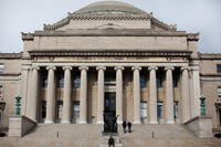 A man is dwarfed by the Columbia University Library as he sits outside the building, Saturday, Feb. 25, 2012, in New York. (AP Photo/John Minchillo)