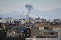 People watch from a rooftop as a plume of smoke rises after a strike in Tehran, Iran, Sunday, March 1, 2026. (AP Photo/Vahid Salemi)