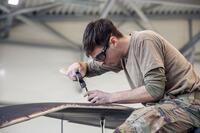An airman works on helicopter blades.