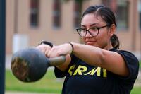 A soldier in a PT uniform swings a kettlebell.