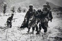 Two Army captains carry an exhausted Soldier off the battlefield in Korea. (U.S. Army photo)