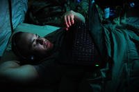 Soldier in bed with a laptop and headphones.