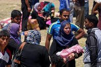 Displaced Iraqis from Ramadi rest before crossing the Bzebiz bridge after spending the night walking towards Baghdad, as they flee their hometown, 65 km west of Baghdad, Iraq, Saturday, May 16, 2015. (AP Photo/ Hadi Mizban)