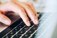 Hands typing on laptop