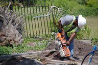 A construction worker using a power tool next to a pile of dirt.