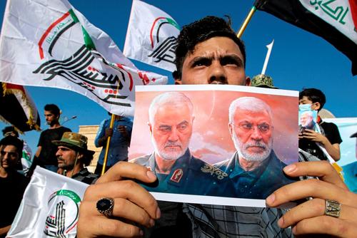 A supporter of an Iran-backed militia holds a poster of Iranian General Qassem Soleimani.