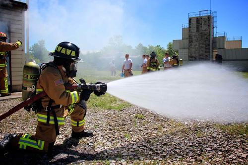 Air Force firefighter sprays water from the nozzle during training exercise