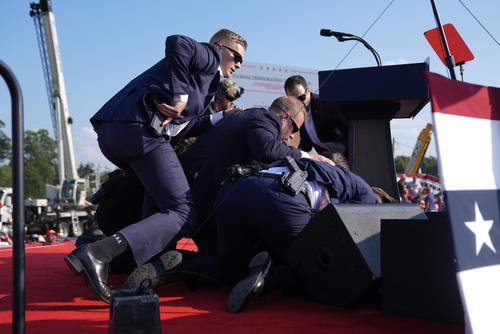 Donald Trump is covered by U.S. Secret Service agents at a campaign rally.